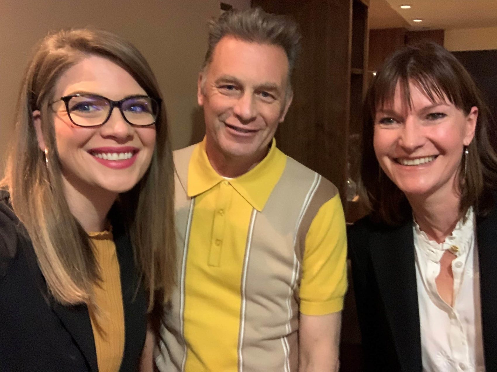 Erin is wearing a black blazer and yellow top, Chris is wearing a yellow and grey polo shirt and Sian a black blazer and white shirt. The image is taken as a selfie.